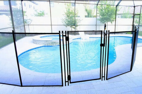 A pool area featuring a fenced perimeter and a pool table nearby, emphasizing recreational space and safety.