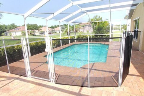 A pool surrounded by a patio area, featuring a screen for shade and relaxation.