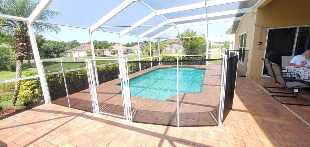 A pool surrounded by a patio area, featuring a screen for shade and relaxation.